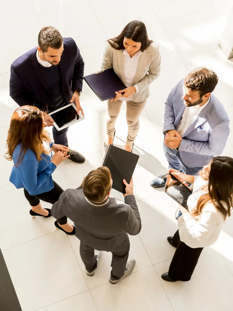 Six coworkers, standing in a circle, discussing something.